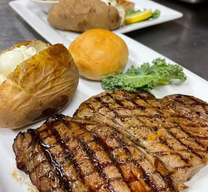 Charbroiled steak with a loaded baked potato and a yeast roll at Grecian Steak House